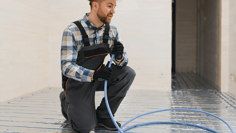 Heating engineer installing water underfloor heating system - request a quote