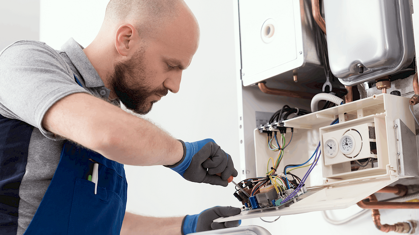 Boiler engineer Man fixing a boiler from below | Request a quote