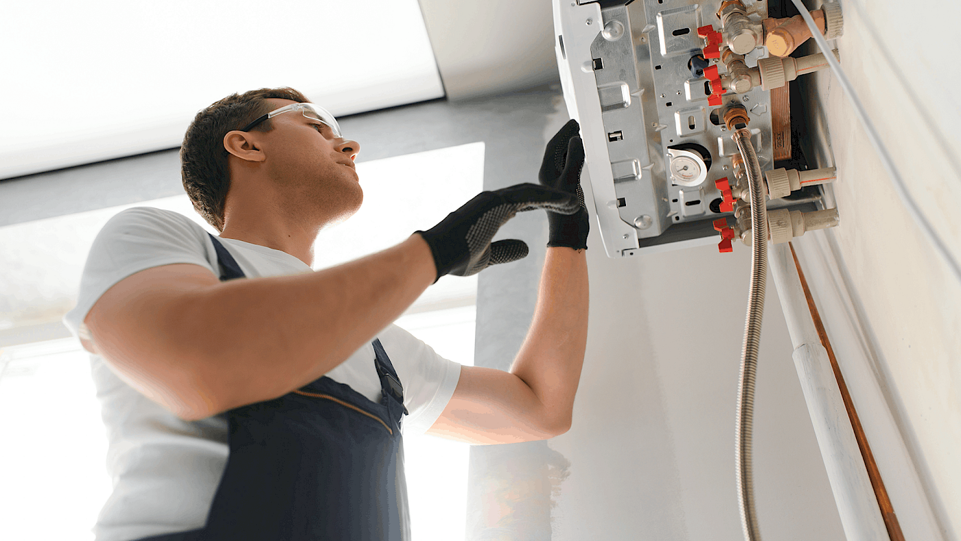 Engineer fixing a boiler Man fixing a boiler from below | Request a quote