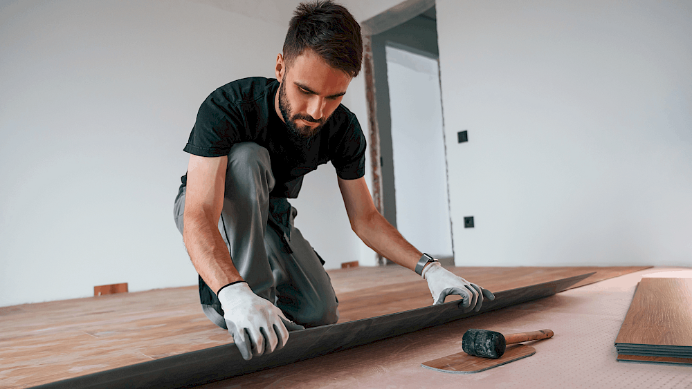 Carpenter installing wooden flooring in home - request a quote
