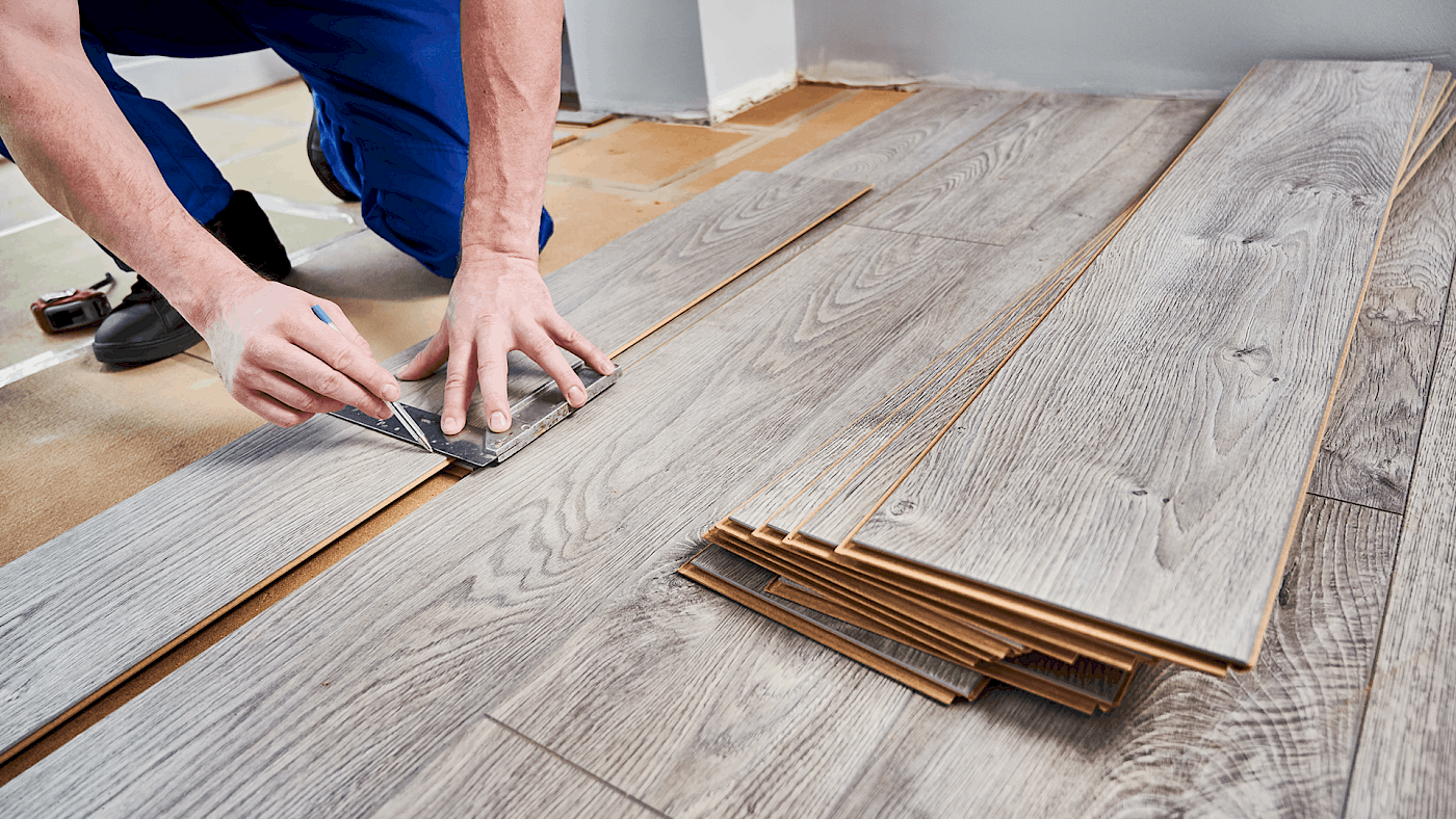 Carpenter laying hardwood floorboards in living room - request a quote